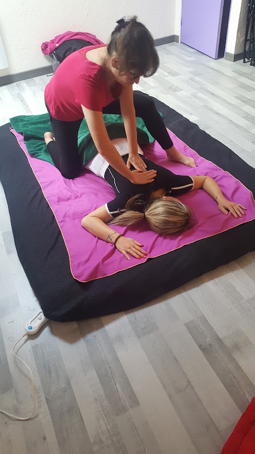 Photo de Muriel Depauw, praticienne massant au sol sur futon, posture ancrée et dos droit, illustrant l’utilisation du poids du corps pour un massage fluide sans tension.