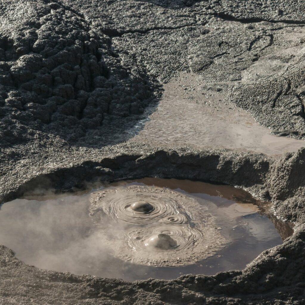 Marre de boue en ébullition, avec des bulles qui remontent à la surface, symbolisant les émotions enfouies qui commencent à remonter et le déclenchement du processus intérieur de transformation.